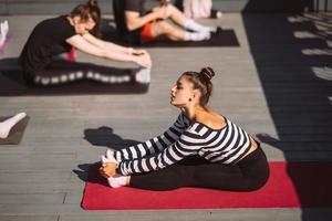 mujer yogui y grupo diverso de deportistas practicando yoga foto