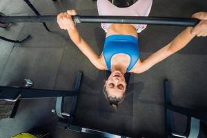 Woman doing exercises with barbell on a bench press training photo