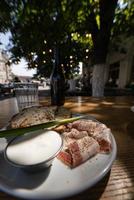 vista de cerca rebanadas de carne de tocino ahumado con pan negro integral de centeno, cebolla verde y crema agria en la mesa. foto