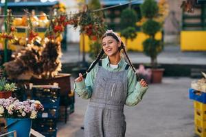 Playful farmer woman in denim overalls smiling sincerely while posing. photo