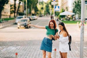 Two tourist friends consulting an online guide on a smart phone in the street photo