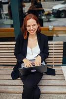 mujer trabajando en una laptop escribiendo sentada en un café bebiendo café foto