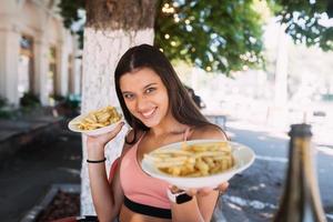 Young women hold french fries on white plates. Street cafe photo