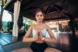 Young woman sitting in lotus position with hands in namaste.