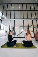 Two young women meditating in lotus pose with hands in namaste. photo