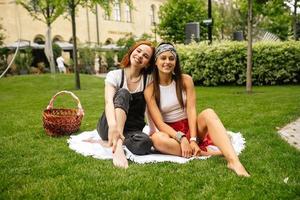 Two women having picnic together, sitting on the plaid photo