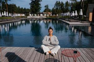 Young fitness woman doing her morning yoga near the pool photo