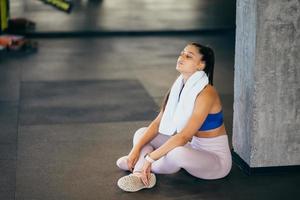 Healthy young female sitting relaxed after training in gym. photo