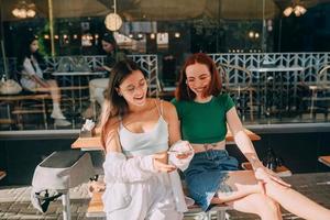 chicas que usan teléfonos inteligentes mientras están sentadas en el café al aire libre foto