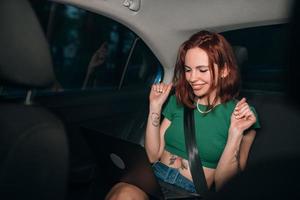 Beautiful woman is using laptop while sitting on back seat photo