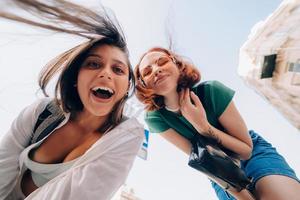 Two friends looks down outdoors in the street at camera photo