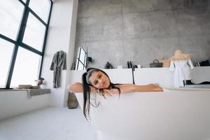 Relaxed lady taking bath, enjoying and relaxing while lying in bathtub photo