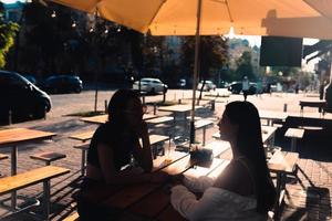 Two pretty girlfriends talking while sitting in a bar outdoors photo