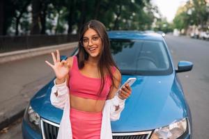 Woman using mobile phone near car at the street photo