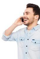 Good  talk. Portrait of cheerful young man talking on the mobile phone and smiling while standing against white background photo