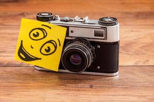 Retro style and cheerful smile. Close-up ofretro camera with adhesive note on it photo