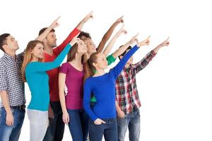 Is it a plane Group of cheerful young multi-ethnic people standing close to each other and pointing away while standing isolated on white photo