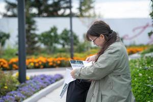 A girl sits on a bench on the street with documents in her hands and using her phone photo