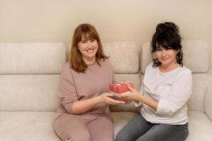 two woman, mother and daughter give gifts to each other and consider them, the concept of giving gifts, family holidays. photo