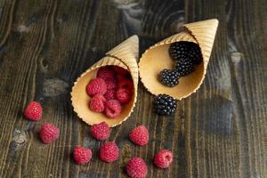 Red ripe raspberries with waffle cups on a black table photo