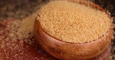 Pour natural brown cane sugar into a wooden bowl photo
