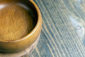 Wooden bowl on wooden table, empty round bowl for groceries and food photo