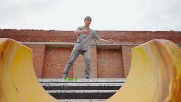 jeune danseur de rue élégant en vêtements gris danse sur le fond d'un mur de briques. ralenti video