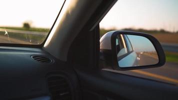 visie van de kant venster van een auto het rijden snel langs de snelweg gedurende een mooi zonsondergang. reizen reis en avontuur concept. video