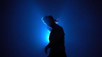silueta, hombre bailarín callejero bailando con estilo en una habitación llena de humo con luz de neón azul de respaldo. video