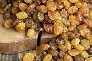 Dried yellow golden raisins on a board photo