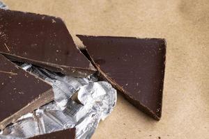 A broken chocolate bar in a paper and foil package photo