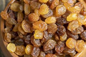 Dried yellow golden raisins on a board photo