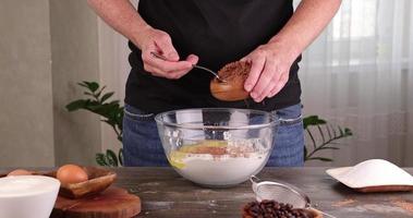 A man pours cocoa in a bowl of flour with sugar while cooking a cake photo