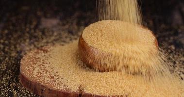 Pour natural brown cane sugar into a wooden bowl photo