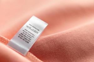 White laundry care washing instructions clothes label on pink cotton shirt photo