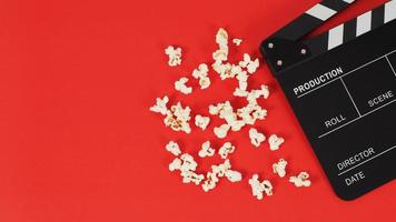 Black Clapper board or movie slate and popcorn on a red background. photo