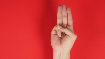 A hand sign of 3 fingers point upward meaning three, third or use in protest.It put on red background photo