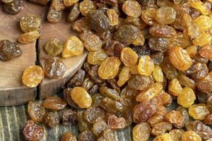 Dried yellow golden raisins on a board photo