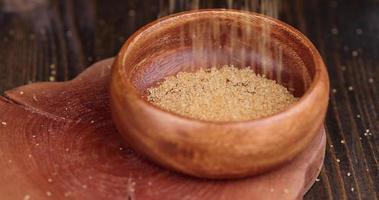 Pour natural brown cane sugar into a wooden bowl photo