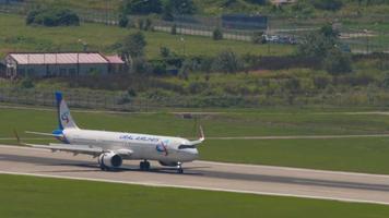 SOCHI, RUSSIA JULY 28, 2022 - Airbus A320 of Ural Airlines braking after landing, arrival at Sochi International Airport. Airplane on the runway. Raised flaps. Tourism and travel concept video