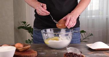 A man pours cocoa in a bowl of flour with sugar while cooking a cake photo
