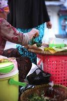 una anciana indonesia está preparando platos de pecel para los clientes. la cocina pecel es una comida tradicional de indonesia foto