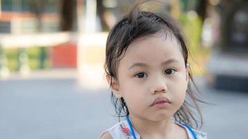 Headshot of sad 4 years old cute baby Asian girl, little toddler child with adorable short hair making frustrated face, looking camera with copy space background. photo