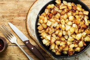 Baked fried potatoes in iron skillet photo