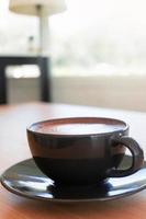 hot organic cocoa with foam froth art in black ceramic cup photo