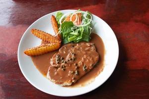 pork chop steak on white plate with french fries and salad photo