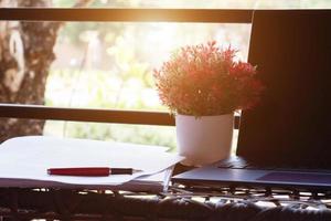 red pen on blurred paperwork next to laptop on table photo