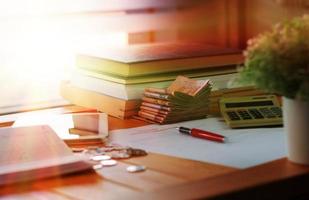 banknotes and books on wooden table with blurred coins and paperwork photo