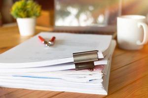 paperworks with black paperclips on top on wooden table photo