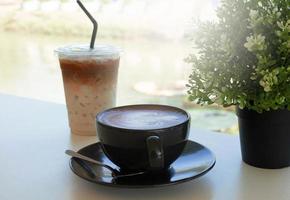 hot cocoa with foam froth art in black ceramic cup on white table photo